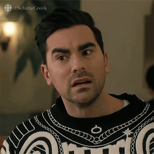A Man With A Beard Is Wearing A Black And White Sweater And Making A Funny Face . GIF