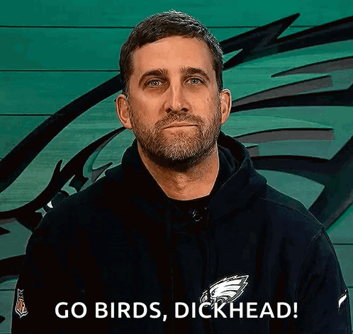 A Man With A Beard Is Wearing A Black Hoodie And Says `` Go Birds , Dickhead '' . GIF