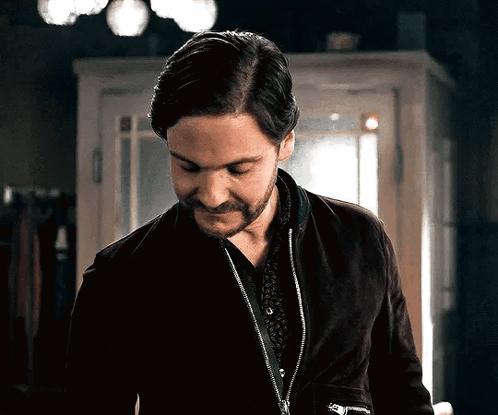 A Man With A Beard Is Wearing A Black Jacket And A Black Shirt GIF