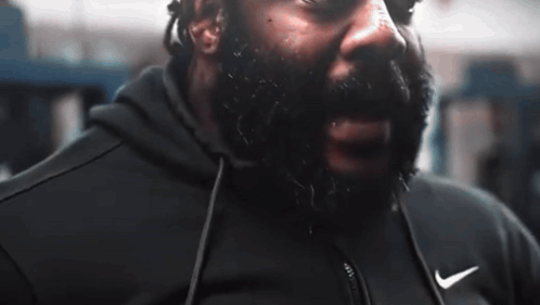 A Man With A Beard Is Wearing A Black Nike Jacket GIF