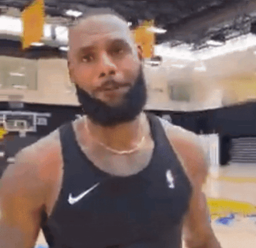 A Man With A Beard Is Wearing A Black Nike Tank Top . GIF