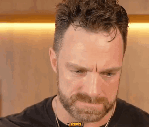 A Man With A Beard Is Wearing A Black Shirt That Says ' Rude ' On The Collar GIF
