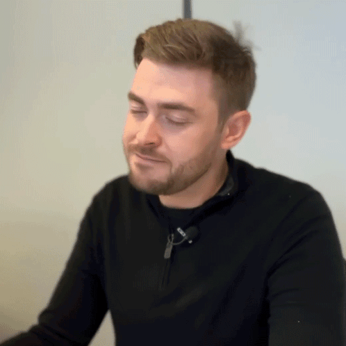 A Man With A Beard Is Wearing A Black Sweater With A Zipper On The Front GIF