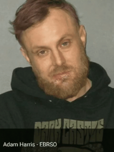 A Man With A Beard Is Wearing A Black Sweatshirt With The Name Adam Harris On It GIF