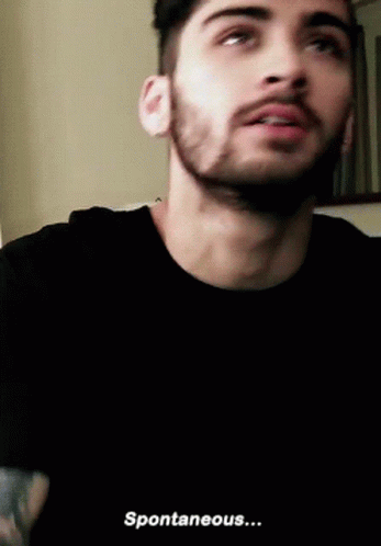 A Man With A Beard Is Wearing A Black T-Shirt And Says Spontaneous . GIF