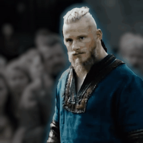 a man with a beard is wearing a blue shirt and looking at the camera