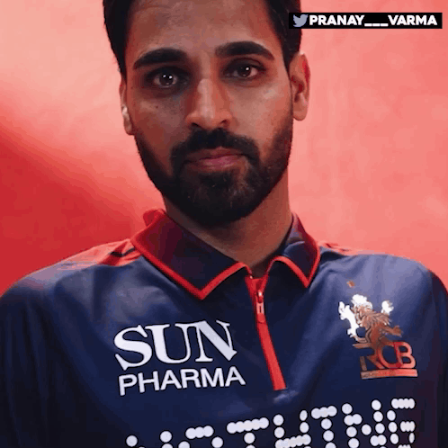 a man with a beard is wearing a blue shirt that says sun pharma
