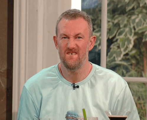 A Man With A Beard Is Wearing A Blue Shirt With A Microphone On His Neck GIF