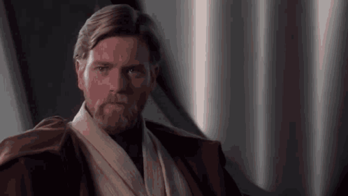 A Man With A Beard Is Wearing A Brown Jacket And A White Scarf Around His Neck . GIF