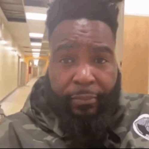 A Man With A Beard Is Wearing A Camouflage Jacket GIF
