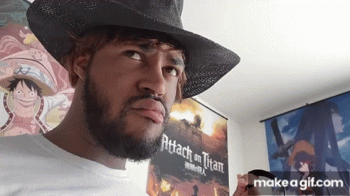 A Man With A Beard Is Wearing A Cowboy Hat And Holding A Cup In Front Of A Poster For Attack On Titan . GIF