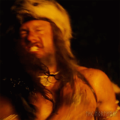 A Man With A Beard Is Wearing A Fur Hat With A Wolf Head GIF