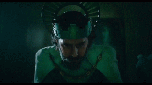 A Man With A Beard Is Wearing A Green Crown And A Chain Around His Neck . GIF