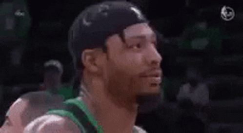 A Man With A Beard Is Wearing A Green Shirt And A Black Hat And Smiling . GIF
