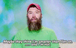 A Man With A Beard Is Wearing A Green Shirt And Red Hat GIF