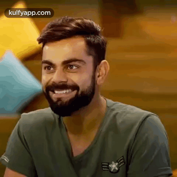 a man with a beard is wearing a green shirt and smiling .