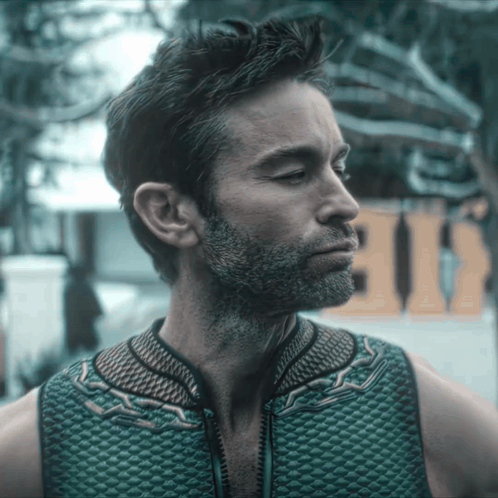 A Man With A Beard Is Wearing A Green Vest With A Zipper GIF