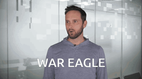 A Man With A Beard Is Wearing A Grey Shirt That Says War Eagle On It GIF