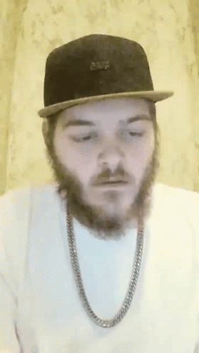 a man with a beard is wearing a hat and chain