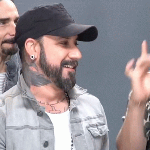 A Man With A Beard Is Wearing A Hat And Earrings GIF