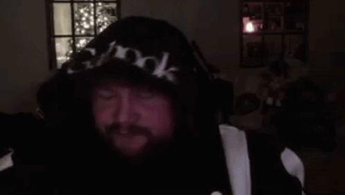 A Man With A Beard Is Wearing A Hoodie And Headphones And Making A Funny Face . GIF