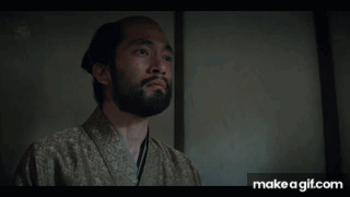 A Man With A Beard Is Wearing A Kimono And Looking At Something GIF