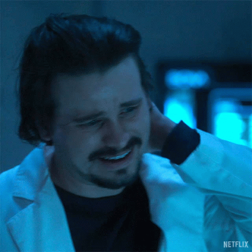 a man with a beard is wearing a lab coat and smiling while holding his neck .