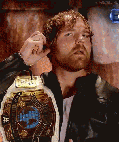 A Man With A Beard Is Wearing A Leather Jacket And Holding A Wrestling Championship Belt . GIF