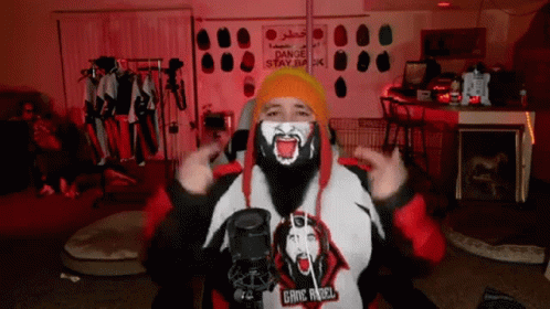 A Man With A Beard Is Wearing A Mask And A Hoodie That Says Gang Angel GIF