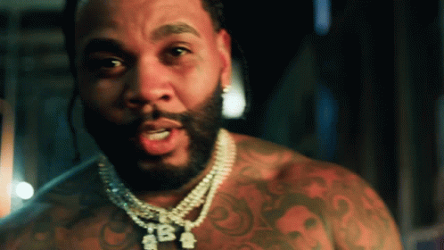 A Man With A Beard Is Wearing A Necklace That Says Tba On It GIF