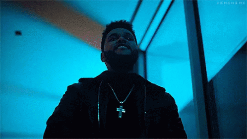 A Man With A Beard Is Wearing A Necklace With A Cross On It And Smiling . GIF