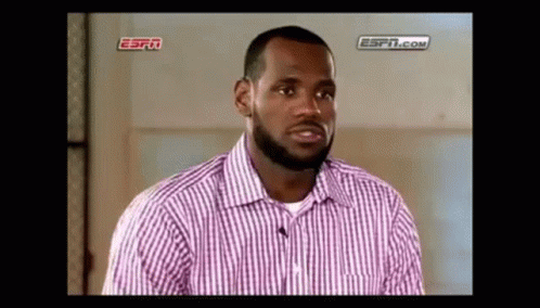 a man with a beard is wearing a pink and white striped shirt and talking to a microphone .