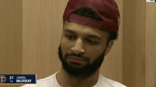 A Man With A Beard Is Wearing A Red Hat And The Name Jamal Murray Is On A Sign GIF