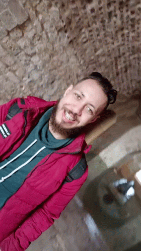 A Man With A Beard Is Wearing A Red Jacket That Says Reebok GIF