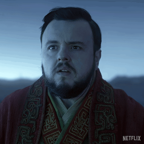 A Man With A Beard Is Wearing A Red Robe With A Netflix Logo On The Bottom GIF