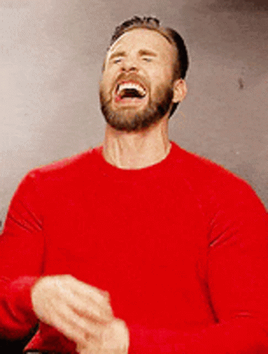 A Man With A Beard Is Wearing A Red Shirt And Laughing . GIF