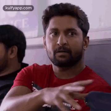 A Man With A Beard Is Wearing A Red T-Shirt And Pointing His Finger . GIF