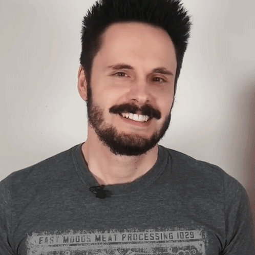 A Man With A Beard Is Wearing A Shirt That Says Meat Processing GIF