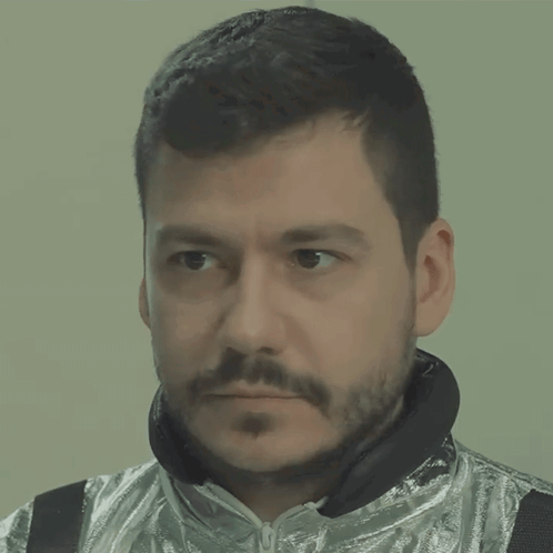 A Man With A Beard Is Wearing A Silver Jacket And Black Headphones GIF
