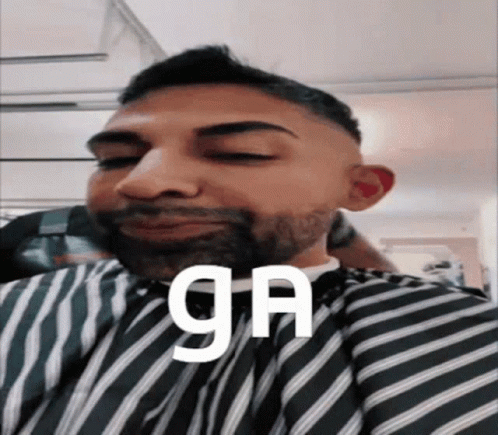 A Man With A Beard Is Wearing A Striped Cape And The Word Ga Is On His Face GIF