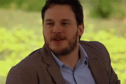 A Man With A Beard Is Wearing A Suit And A Blue Shirt And Is Smiling . GIF