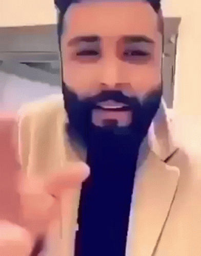 A Man With A Beard Is Wearing A Suit And Giving A Peace Sign GIF