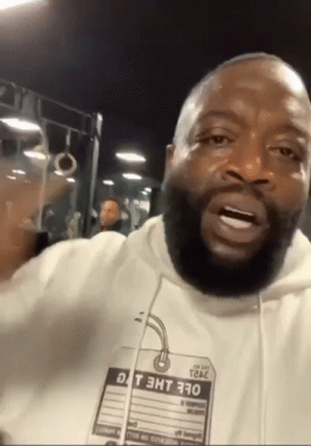 A Man With A Beard Is Wearing A White Hoodie With A Tag That Says Dt 3Ht 370 On It GIF