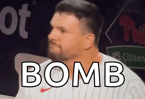 A Man With A Beard Is Wearing A White Jersey With The Word Bomb On It . GIF
