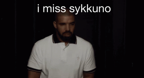 A Man With A Beard Is Wearing A White Polo Shirt With The Words I Miss Sykkuno On The Bottom GIF