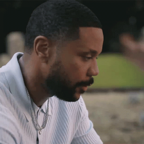 A Man With A Beard Is Wearing A White Shirt And A Gold Chain Around His Neck GIF