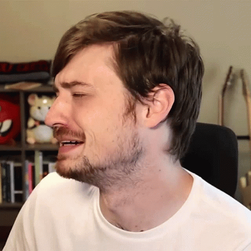A Man With A Beard Is Wearing A White Shirt And Making A Face GIF
