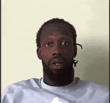 A Man With A Beard Is Wearing A White Shirt And Making A Funny Face GIF