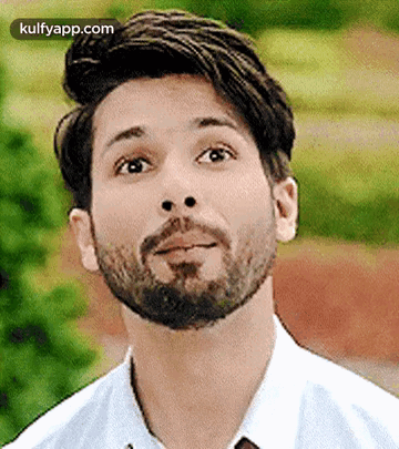 A Man With A Beard Is Wearing A White Shirt And Tie And Looking Up . GIF