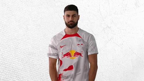 a man with a beard is wearing a white shirt with a red bull on it